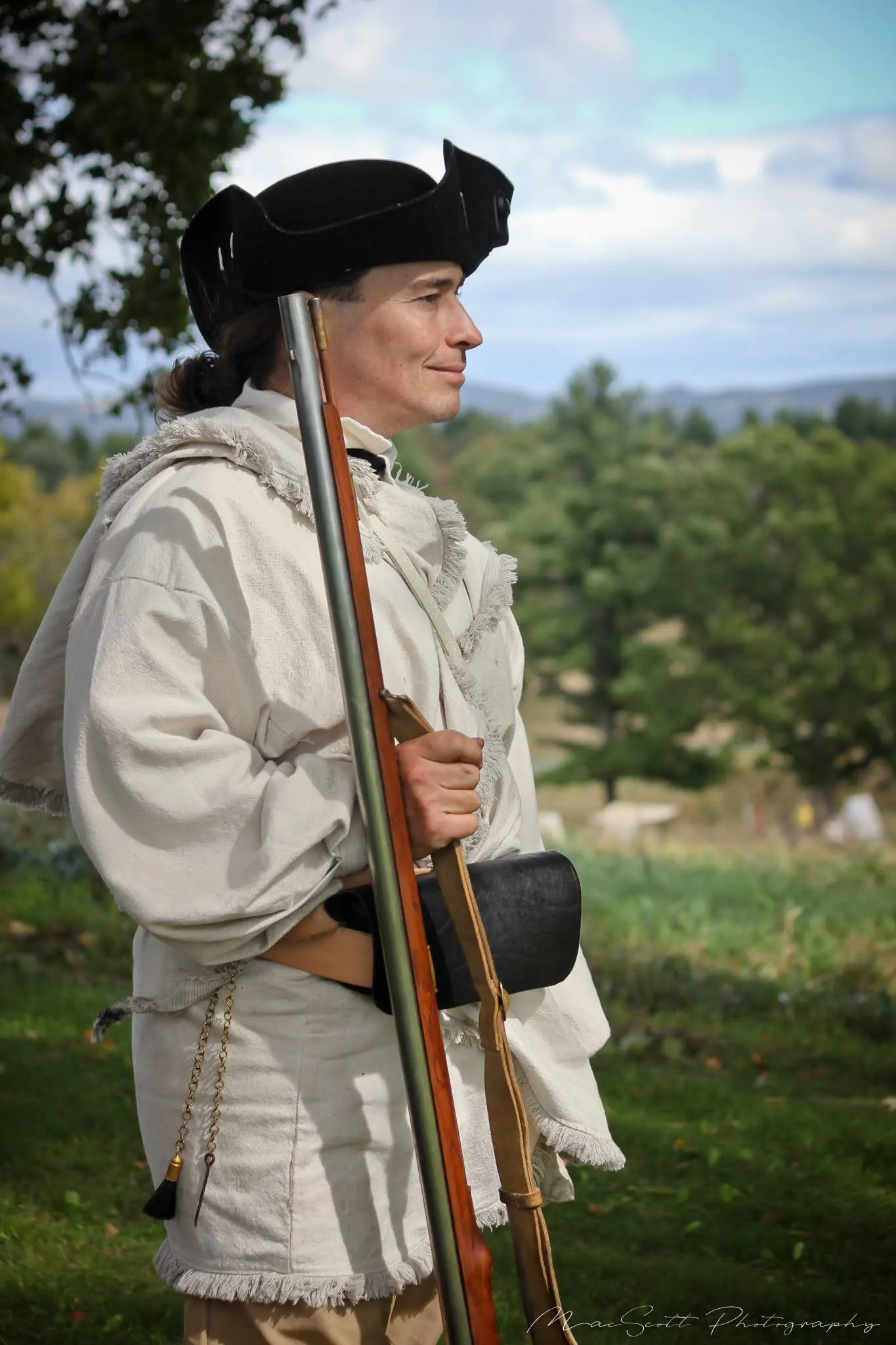 In a cream hunting frock with rifle in the field